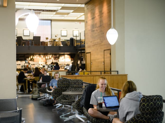 Students do schoolwork at tables beside Starbucks in Cooper Library.