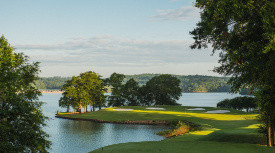 An orange flag with white tiger paw waves in the wind on a hole of the Walker Golf course beside Lake Hartwell.