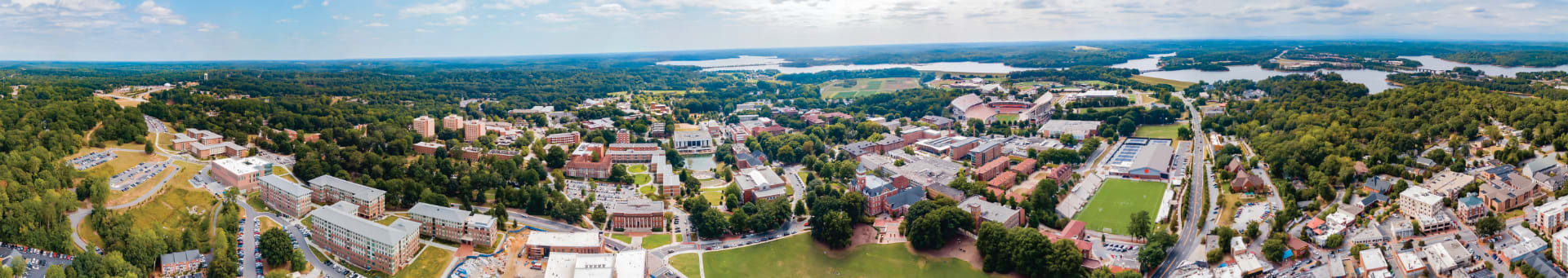 A wide-angle bird's-eye view of the Clemson University campus showing academic buildings, residence halls, athletic fields and Lake Hartwell.