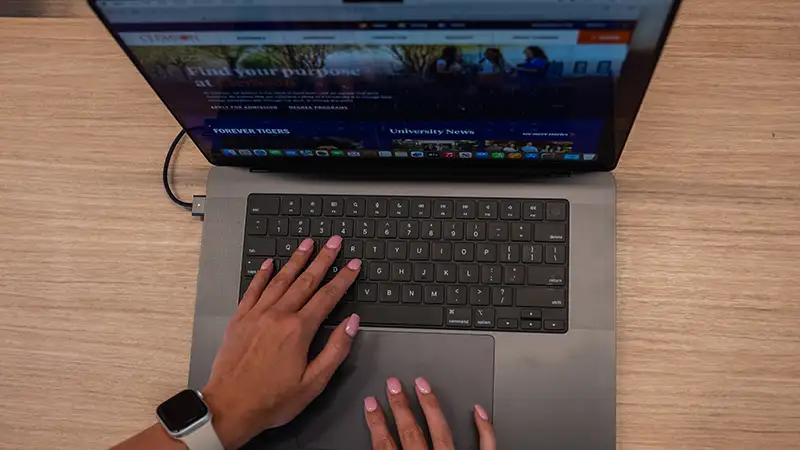 An overhead shot of a pair of hands resting on the keyboard of a laptop.